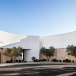 Exterior photography of entrance to a minimalist curved façade/house; day mode frontal street view.
