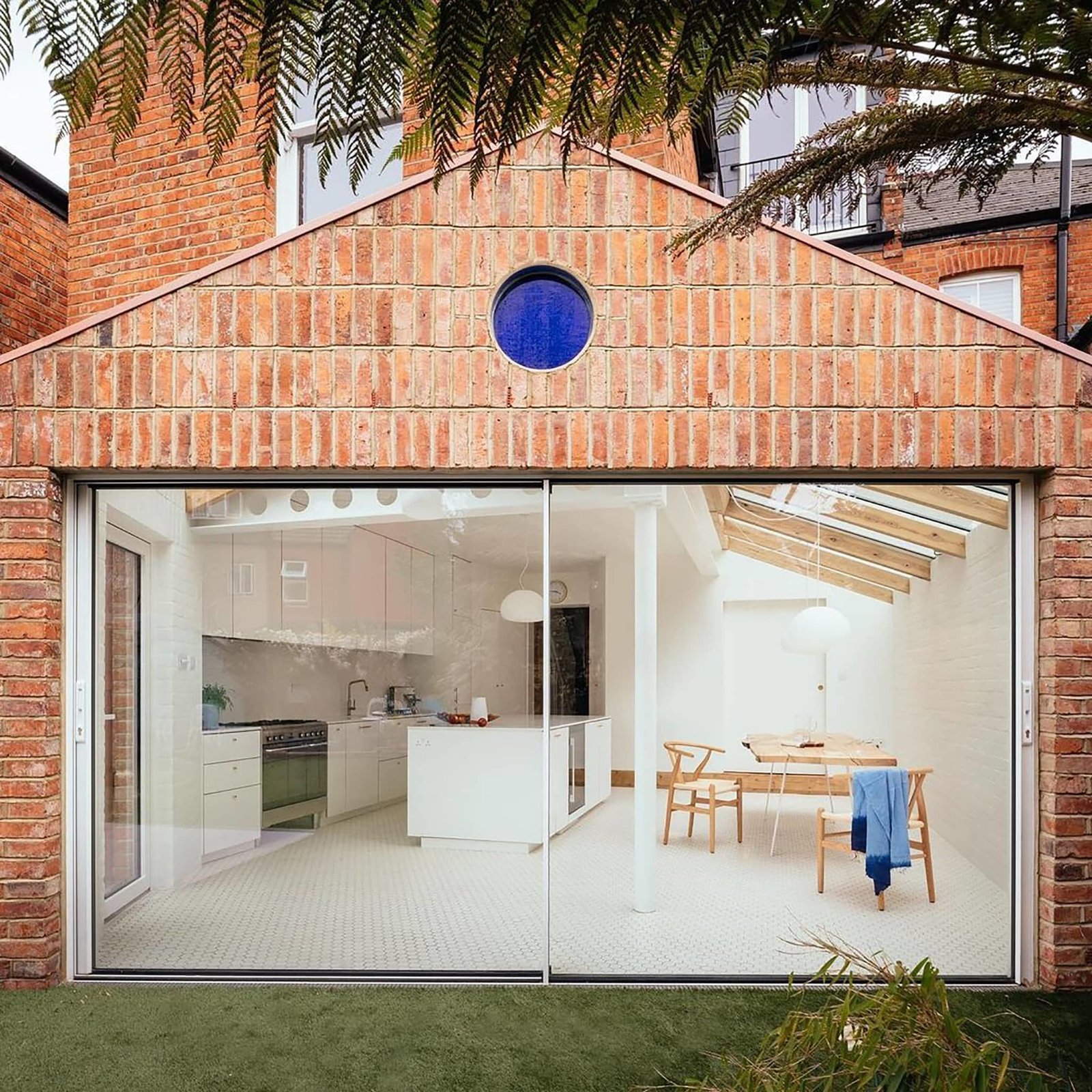 Exterior photography of large window to a renovated Victorian brick house; day mode frontal backyard view.