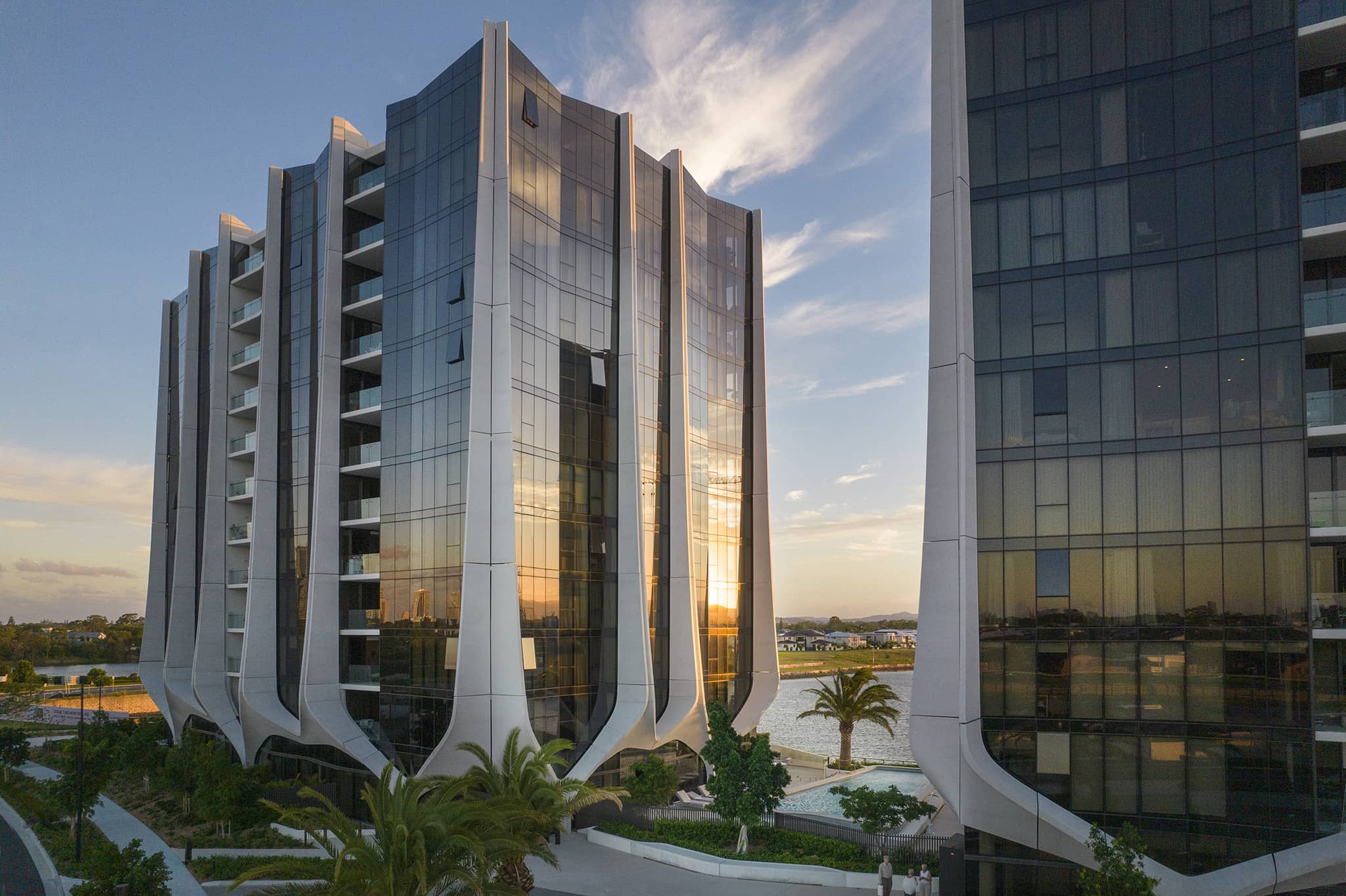 Exterior photography of residential glass façade towers with vertical elements; sunset view.