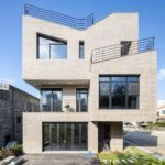 Exterior photography of stacked volumes façade/ house; day mode frontal backyard view.