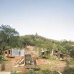 Exterior photography of minimalist concrete cabins; day mode frontal hillside view.