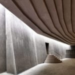 Interior photography of minimalist concrete mosque with concrete walls and gradual scaled ceiling with linear skylight.