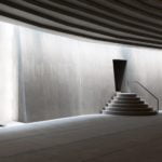 Interior photography of minimalist concrete mosque with concrete walls and gradual scaled ceiling with linear skylight.