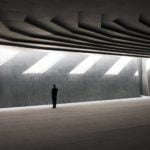 Interior photography of minimalist concrete mosque with concrete walls and gradual scaled ceiling with linear skylight.