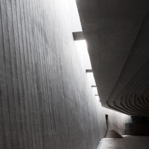 Interior photography of minimalist concrete mosque with concrete walls and gradual scaled ceiling with linear skylight.